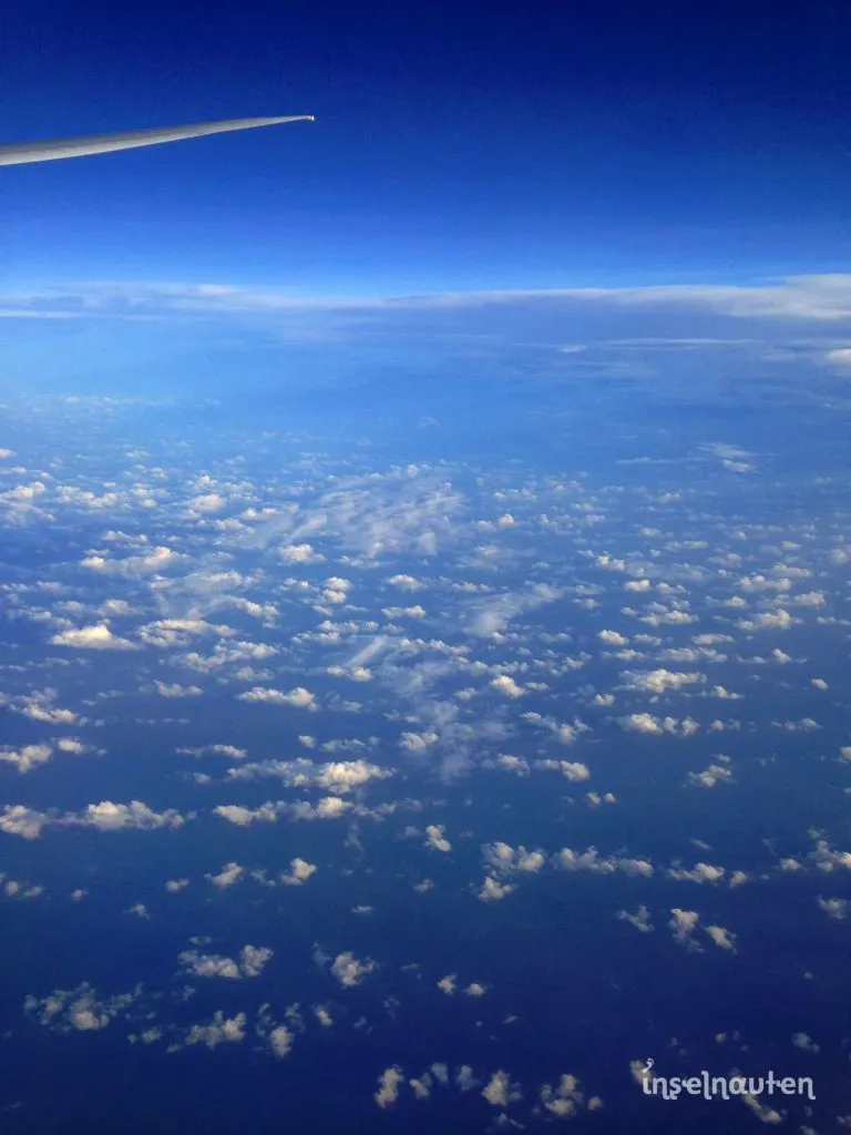 Blick aus dem Flugzeugfenster auf die Tragflächenspitze über dem Ozean