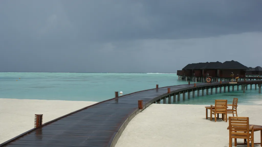 Malediven Regenzeit Wasserbungalow Nasser Holzsteg zu Wasserbungalows unter einem stürmisch-grauen Himmel