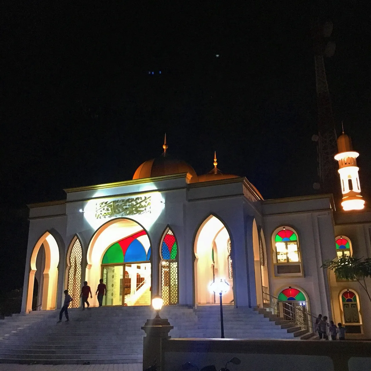 Nachts festlich beleuchtete Moschee mit bunten Fenstern auf einer maledivischen Insel