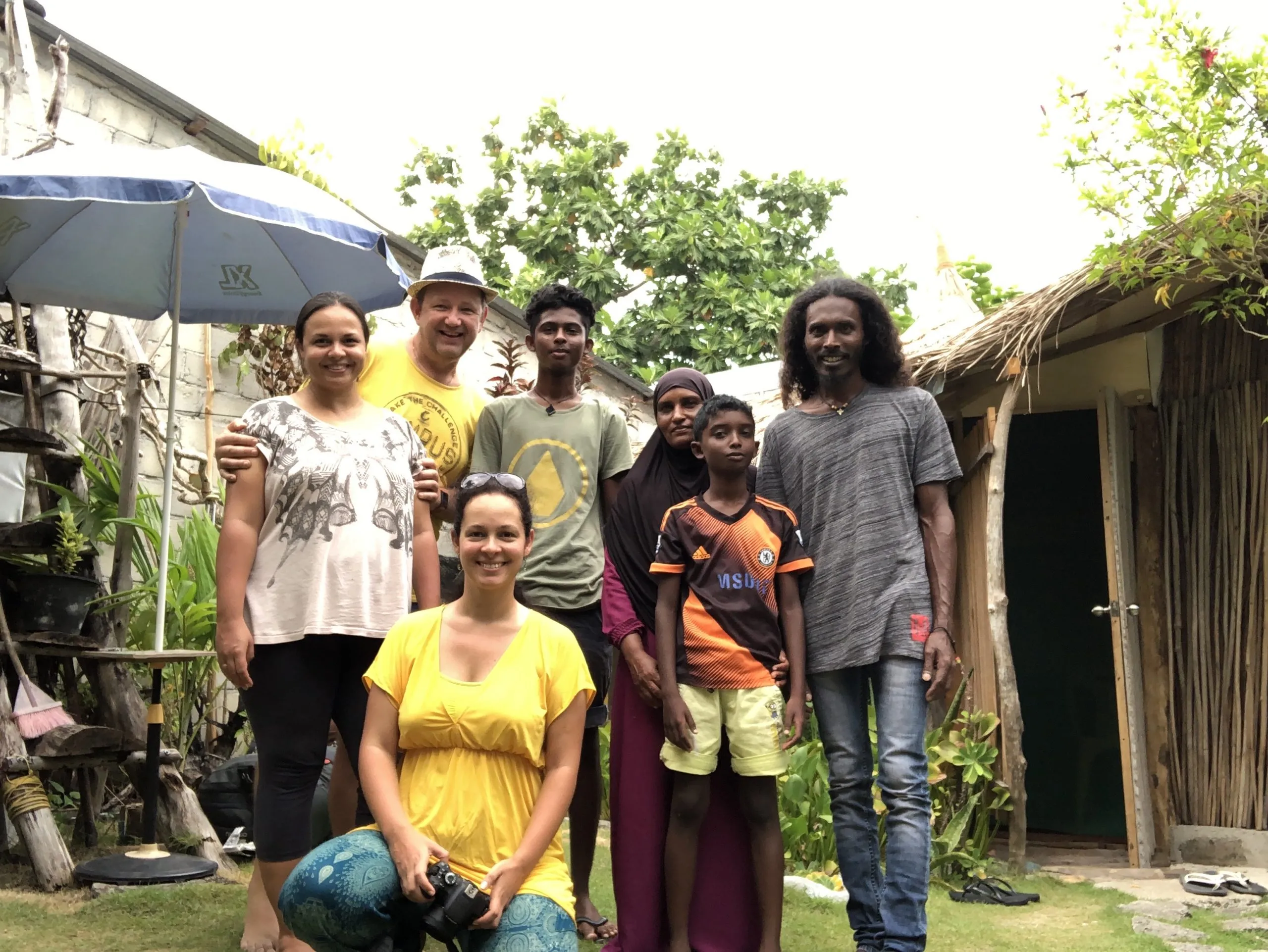 Gäste und die maledivische Gastfamilie zusammen im Garten des Homestays