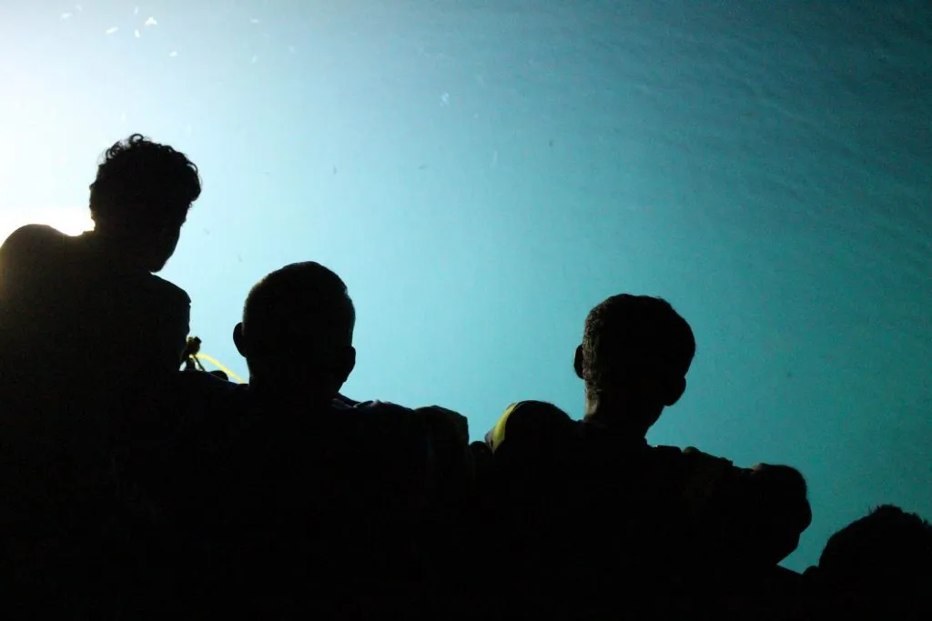 Fischer als Silhouette vor dem angestrahlten Wasser bei der nächtlichen Köderfischsuche