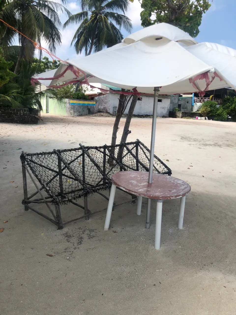 Einfache Sitzecke mit Netzbank und Sonnenschirm am Strand einer Local Island