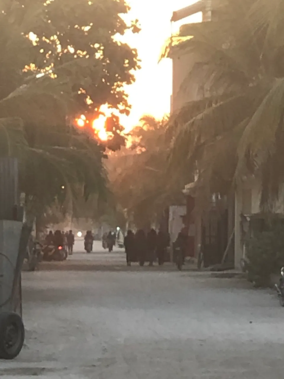Dorfstraße mit Einheimischen und Palmen im Abendlicht auf einer Local Island