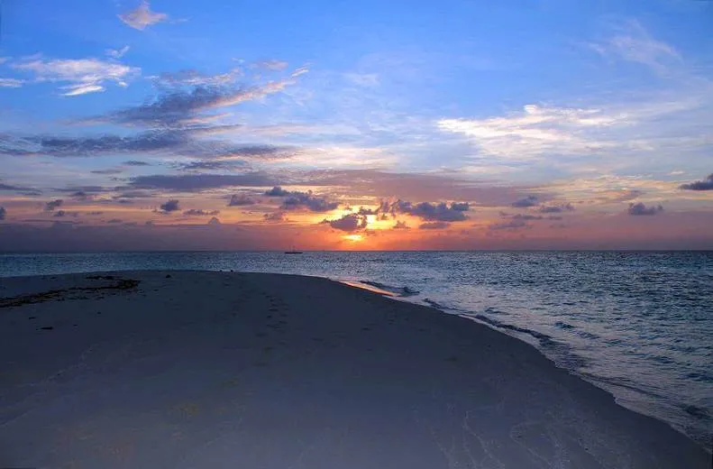 Pastellfarbener Sonnenuntergang über einer Sandbank mit Fußspuren im Sand