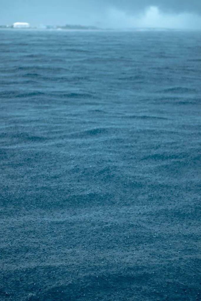 Malediven Regenzeit Kräftiger tropischer Regen prasselt auf das Meer, im Dunst eine Insel