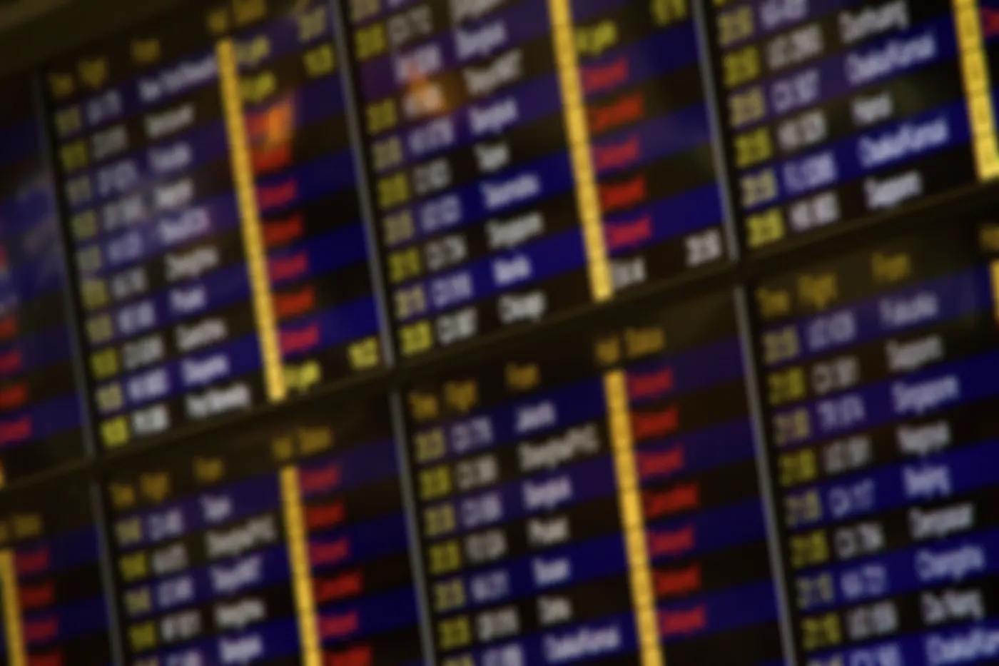 Unscharfer Blick auf eine Anzeigetafel am Flughafen mit zahlreichen rot markierten Delayed- und Cancelled-Meldungen